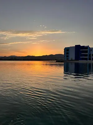 a sunset over a body of water with a building at Chic One-Bedroom with Sea View in Aqaba
