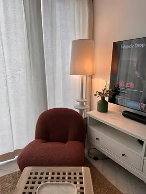 a living room with a red chair and a tv at Chic One-Bedroom with Sea View in Aqaba
