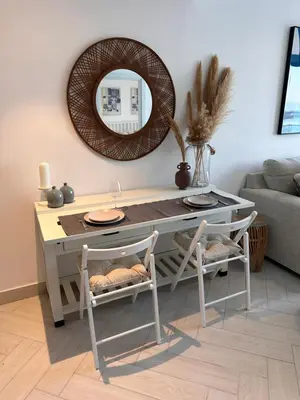 a table with two chairs and a mirror in a living room at Chic One-Bedroom with Sea View in Aqaba