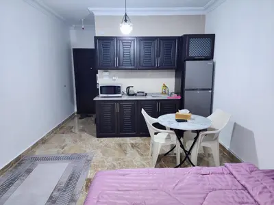 a kitchen with black cabinets and a table with a cake on it at Salo StudioS in Amman