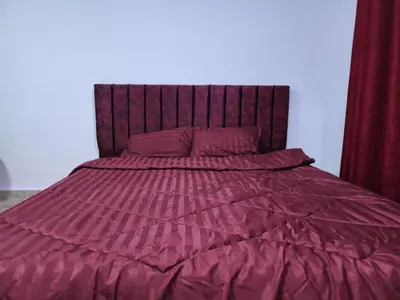 a bed with a purple comforter and red curtains at Salo StudioS in Amman