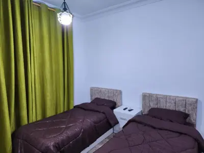a bedroom with two beds and a green curtain at Salo StudioS in Amman