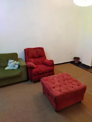 a living room with two chairs and a red ottoman at شقة ام نوارة الحديثة الفارهة spacious economic flat in Amman