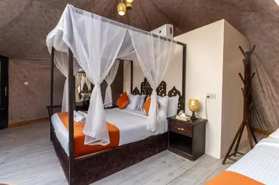 a bedroom with a canopy bed with orange and white pillows at Aladdin Camp in Disah