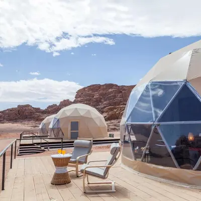 a group of domes in the desert with chairs and a table at Rum Leno Luxure camp in Wadi Rum