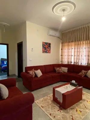 a living room with a red couch and a table at Cozy Flat, Amman Airport in Amman