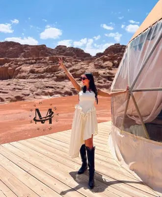 a woman in a white dress standing next to a boat at RUM MARTiN BUBBLES lUXURY CAMP in Wadi Rum