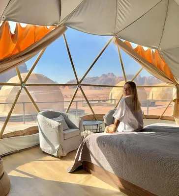 a woman sitting on a bed in a tent at RUM MARTiN BUBBLES lUXURY CAMP in Wadi Rum