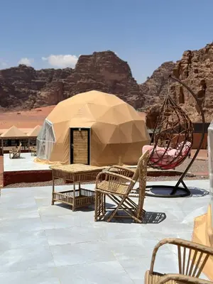 a tent with chairs and a swing in the desert at RUM MARTiN BUBBLES lUXURY CAMP in Wadi Rum