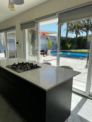 a kitchen with a stove and a view of a pool at Maui Villa by Seahorse in Al Rama