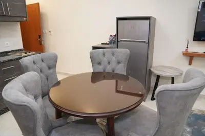 a kitchen with a table and two chairs and a refrigerator at فندق أوتار ذهب in Ma‘ān