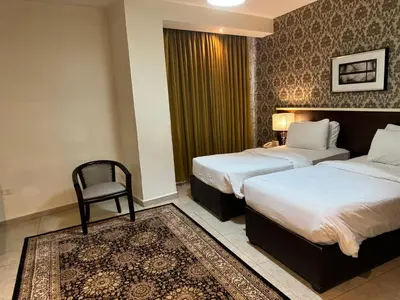 a hotel room with two beds and a chair at City Rose Hotel Suites in Amman