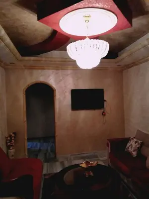 a living room with a chandelier and a tv at zin home in ‘Awjān ash Sharqī