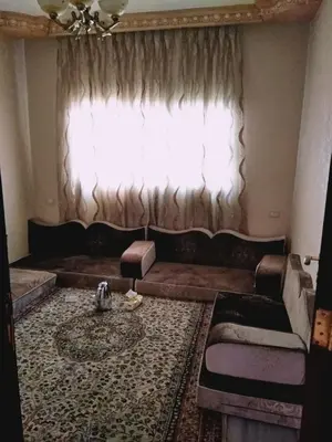 a living room with a couch and a window at zin home in ‘Awjān ash Sharqī