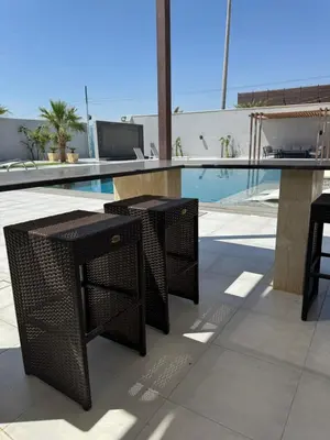 two black wicker tables sitting next to a swimming pool at Sol Villa By Seahorse in Al Rama