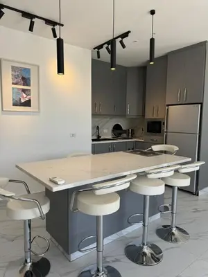 a kitchen with a island with bar stools at Sol Villa By Seahorse in Al Rama