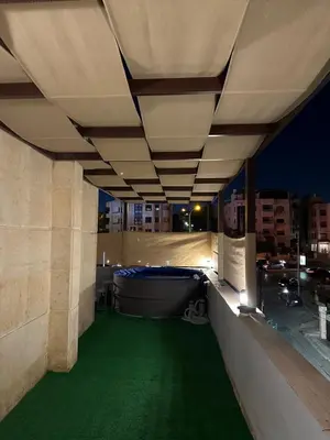 a balcony with green flooring on a building at night at Rooftop pool with terraces F-R in Amman