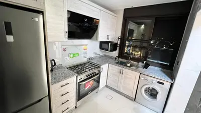 a small kitchen with a stove and a dishwasher at شقة روف بعرفتين اطلالة ساحرة عمو سامي 21 in Amman