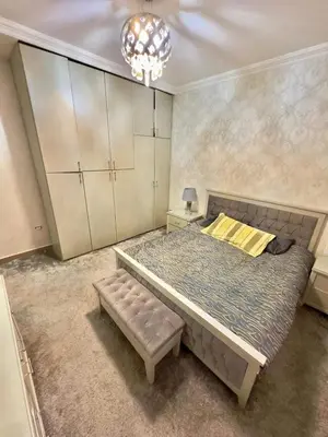 a bedroom with a large bed and a chandelier at olga 300 apertment in Ar Ramthā