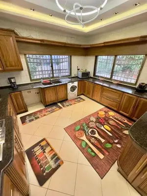 a large kitchen with wooden cabinets and a rug on the floor at olga 300 apertment in Ar Ramthā