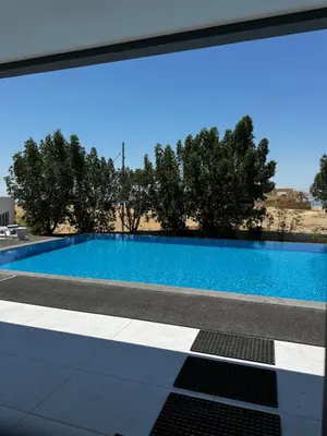 a blue swimming pool with trees in the background at Beit Elhala Villa By Seahorse in Al Rama