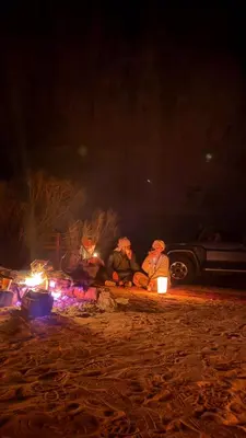 a group of people sitting around a fire at night at Hkaya Rum camp in Wadi Rum