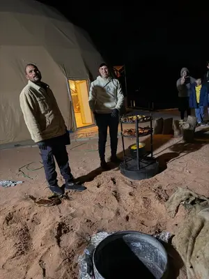 a group of men standing in front of a tent at Hkaya Rum camp in Wadi Rum