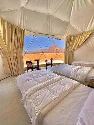 a bedroom with a large white bed and a table at Hkaya Rum camp in Wadi Rum