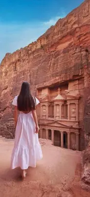 a young girl in a white dress standing in front of a rock wall at Petra Friends House in Petra