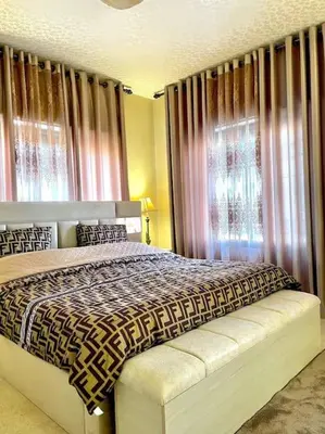 a bedroom with a bed and a window with curtains at Classy 3 Bedroom Apartment in Amman in Ţāb Kirā‘