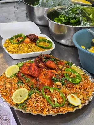 a plate of food with chicken and rice on a table at Rema 120 apertment in Um Qeis