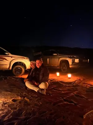 a man and woman sitting in front of a car with candles at Magic mountains rum in Wadi Rum