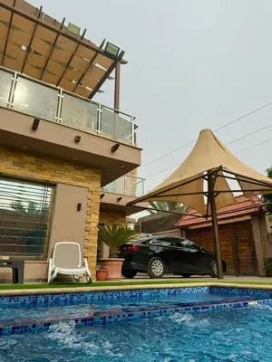 a car parked in front of a house with a pool at Yasmina Chalet in Al Kafrayn