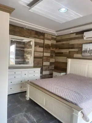a bedroom with a bed and a wooden wall at Yasmina Chalet in Al Kafrayn
