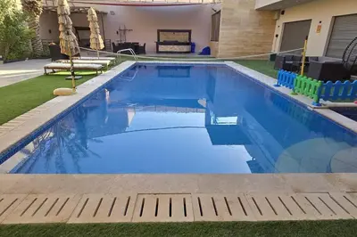 a swimming pool with blue water in a yard at Jumeirah Chalet جميرا شاليه in Amman
