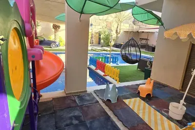 a play area with a pool and an umbrella at Jumeirah Chalet جميرا شاليه in Amman