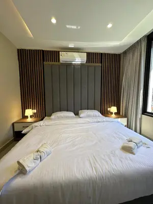 a bedroom with a large white bed with towels on it at Chic Apartments For Rent ave0-1 in Umm Uthainah