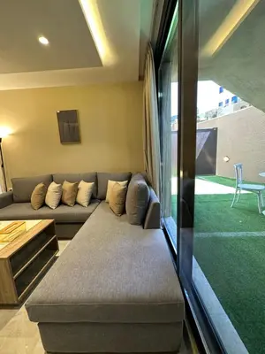a living room with a couch and a large window at Chic Apartments For Rent ave0-1 in Umm Uthainah