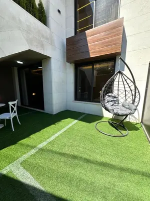 a patio with a swing on the grass at Chic Apartments For Rent ave0-1 in Umm Uthainah
