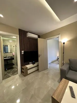 a living room with a couch and a television at Chic Apartments For Rent ave0-1 in Umm Uthainah