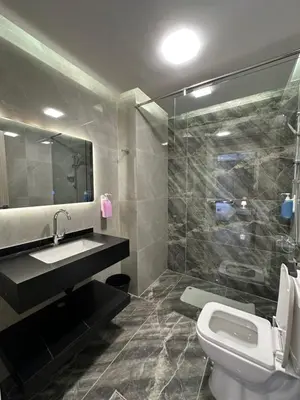 a bathroom with a toilet and a sink and a shower at Chic Apartments For Rent ave0-2 in Umm Uthainah
