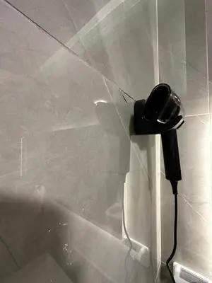 a black phone hanging on the wall of a shower at Chic Apartments For Rent ave0-2 in Umm Uthainah