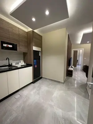 a kitchen with white cabinets and a black refrigerator at Chic Apartments For Rent ave0-4 in Umm Uthainah