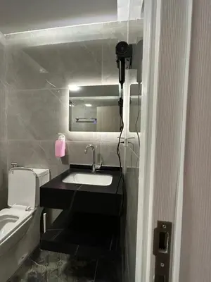 a bathroom with a sink and a toilet and a mirror at Chic Apartments For Rent ave0-4 in Umm Uthainah