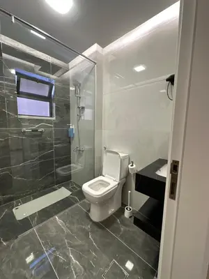 a bathroom with a toilet and a glass shower at Chic Apartments For Rent ave0-6 in Amman