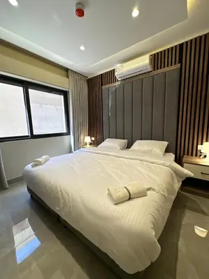 a bedroom with a large white bed and two windows at Chic Apartments For Rent ave0-7 in Umm Uthainah