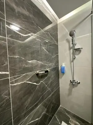 a bathroom with a shower with a black marble wall at Chic Apartments For Rent ave0-7 in Umm Uthainah