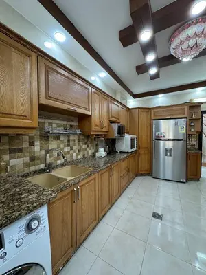 a kitchen with wooden cabinets and a stainless steel refrigerator at شقة مفرشة في الرابية 3 غرف نوم in Amman