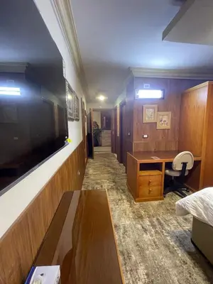 a hotel room with a desk and a tv and a room at Azmal Hotel & Suites in Irbid