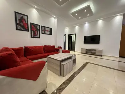 a living room with a red couch and a tv at Secured Compound Hill-view Terrace in Amman